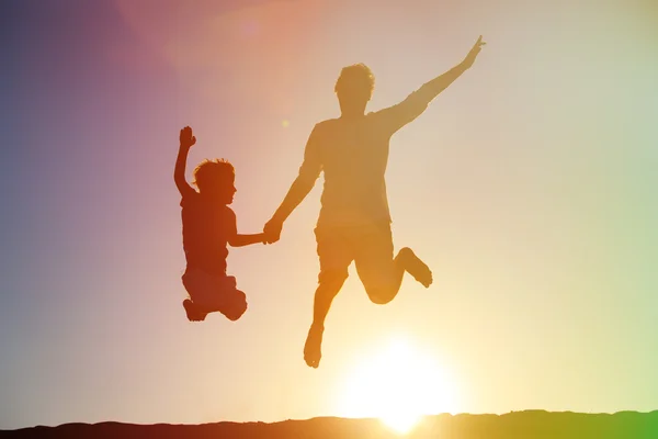 Padre e figlio che saltano al cielo del tramonto — Foto Stock