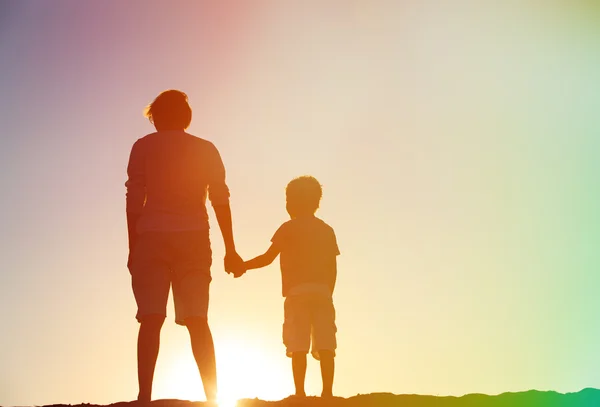 father and son holding hands at sunset