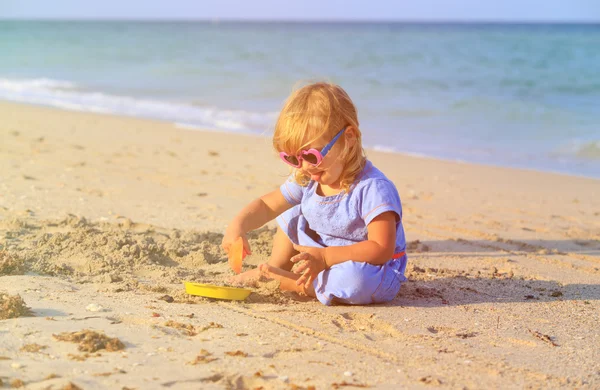 Girl plays with sand on beach — Stock Photo, Image