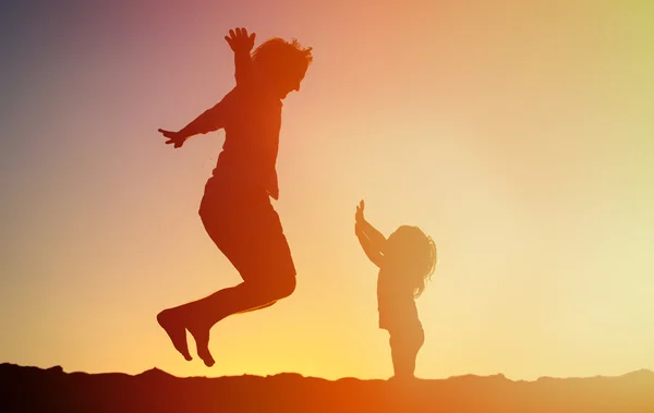 Ojciec i córka skoki o zachodzie słońca — Zdjęcie stockowe