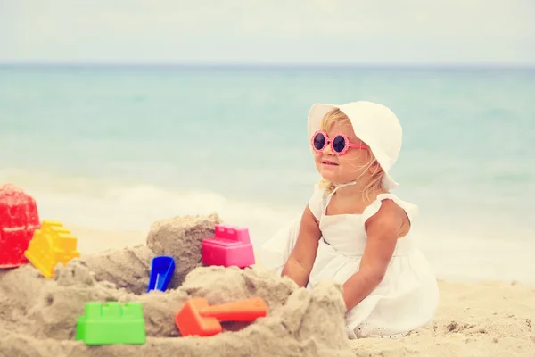 Menina brinca com areia na praia — Fotografia de Stock