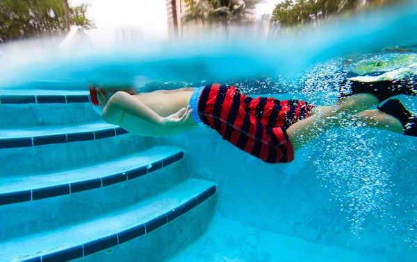 En liten gutt som svømmer under vann – stockfoto