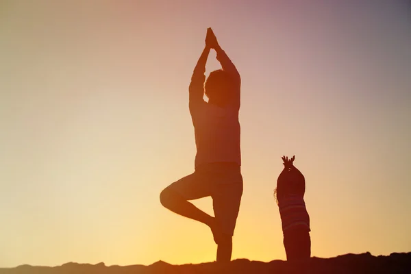 Father and daughter doing yoga at sunset — Stock Photo, Image