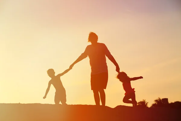 Батько з сином і дочкою грають на заході сонця — стокове фото