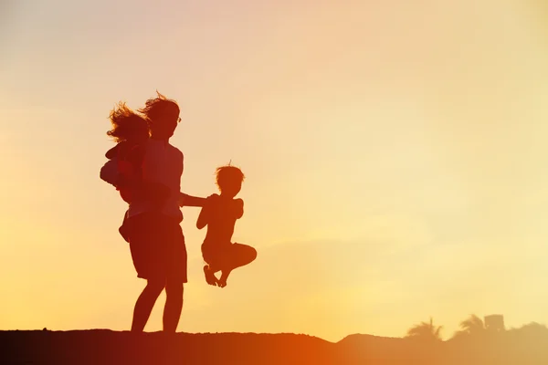 Padre con figlio e figlia saltando al tramonto — Foto Stock