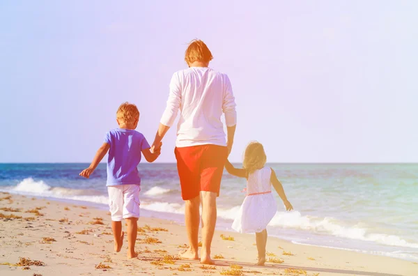 Vader en twee kinderen walking op strand — Stockfoto