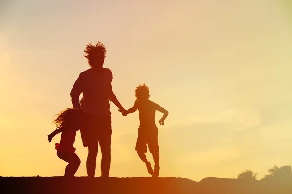 Padre con figlio e figlia saltando al tramonto — Foto Stock