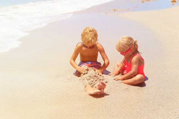 Ragazzo e ragazza giocare con acqua sulla spiaggia — Foto Stock