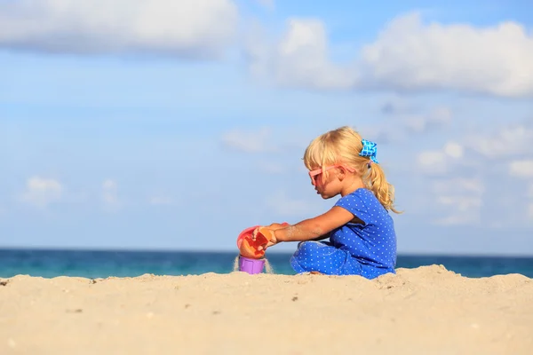 Meisje speelt met zand op strand — Stockfoto