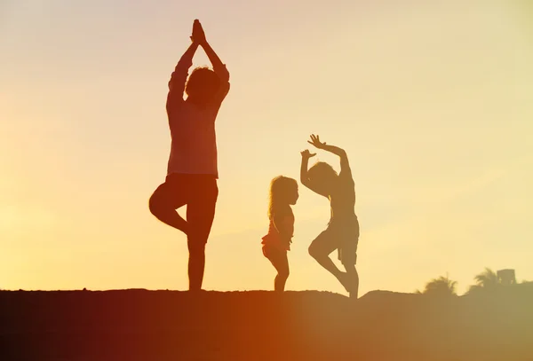 Père avec des enfants faisant du yoga au coucher du soleil — Photo