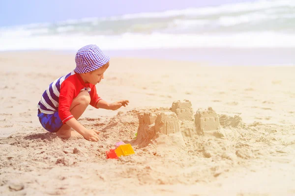 Chlapec hraje s pískem na pláži v létě — Stock fotografie