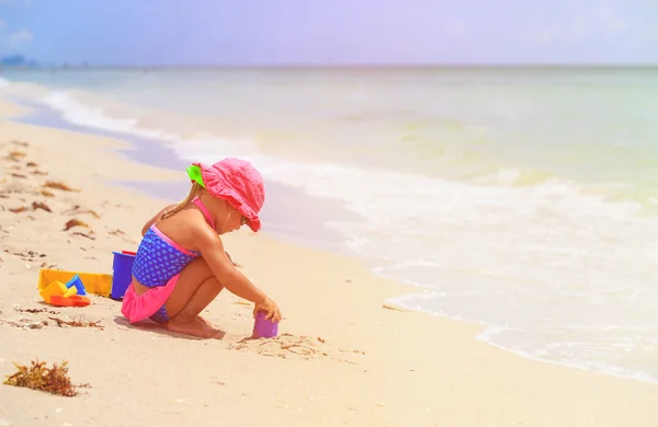 Menina brinca com areia na praia — Fotografia de Stock