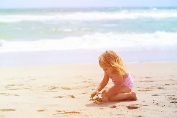 Девушка играет с песком на пляже — стоковое фото