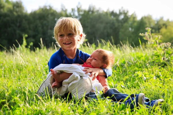 Pojke anläggning nyfödda lillasyster i sommar natur — Stockfoto