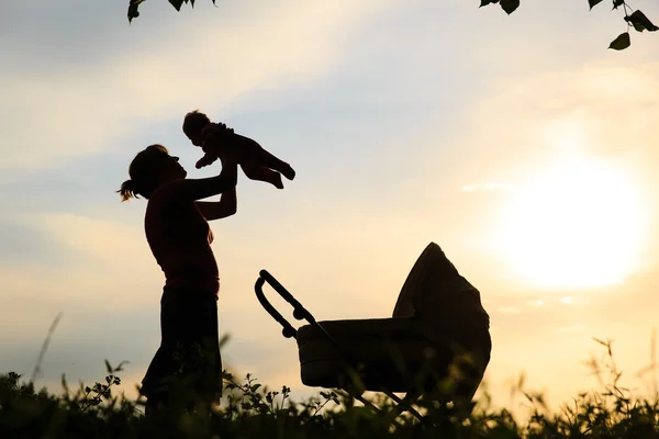 Silhouetten van moeder met baby en wandelwagen — Stockfoto