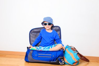 Çocuklar seyahat kavramı - Paketli bavula oturan küçük çocuk