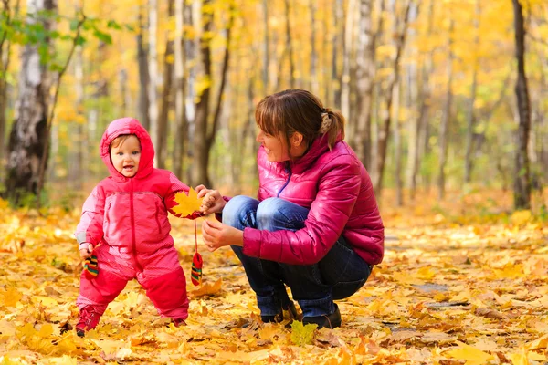 Mother and daughter play in autumn — Stock Photo, Image