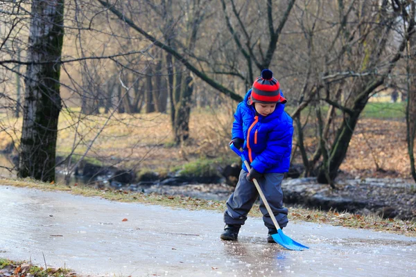 Little boy cleaning ice with spade — Stock Photo, Image