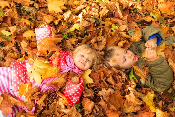 Happy kids having fun in autumn fall leaves — Stock Photo, Image