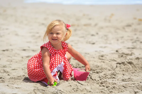Маленькая девочка играет с песком на пляже — стоковое фото