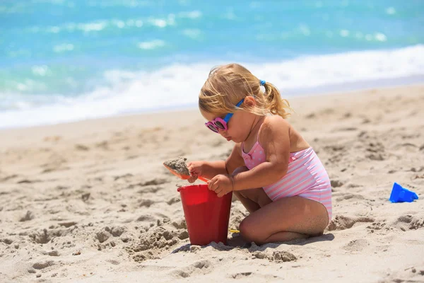 Маленькая девочка играет с песком на пляже — стоковое фото