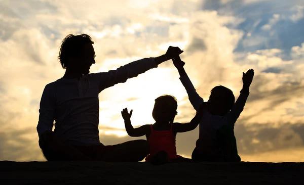 Otec se synem a dcerou siluety play při západu slunce — Stock fotografie