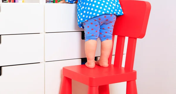 Barnen säkerhet - liten flicka klättring på barnstol — Stockfoto