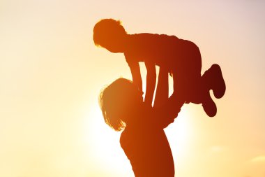 Baba ve küçük oğlu siluetleri günbatımında oynamak