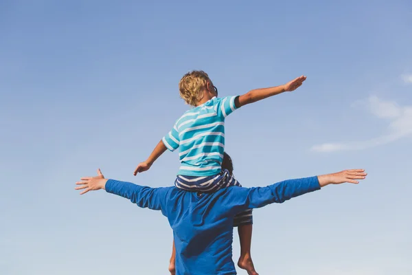 Gelukkig vader en zoon spelen op sky — Stockfoto