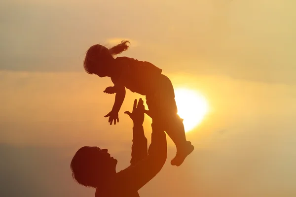 Батько і маленька дочка грають на заході сонця — стокове фото