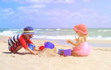 Çocuklar yaz plajında kumla oynarlar.