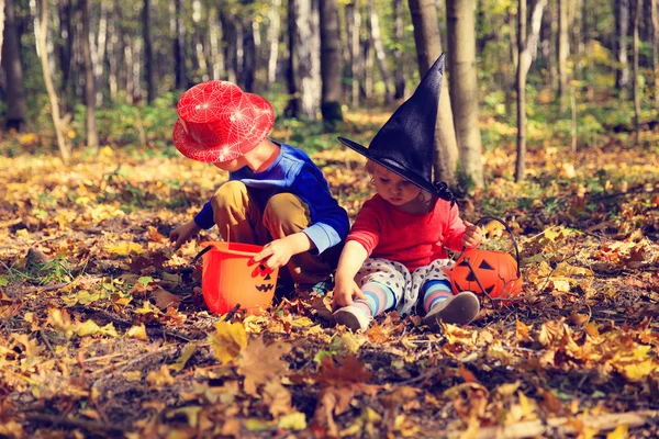 Anak-anak dengan kostum halloween bermain di taman musim gugur, trik atau mengobati — Stok Foto