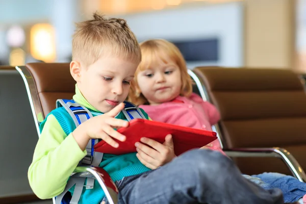 kids looking at touch pad while waiting in the airport