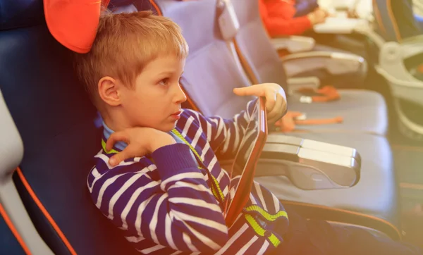 Niño mirando la almohadilla táctil viajando en avión — Foto de Stock