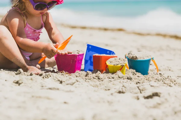 Menina brincar com areia na praia — Fotografia de Stock