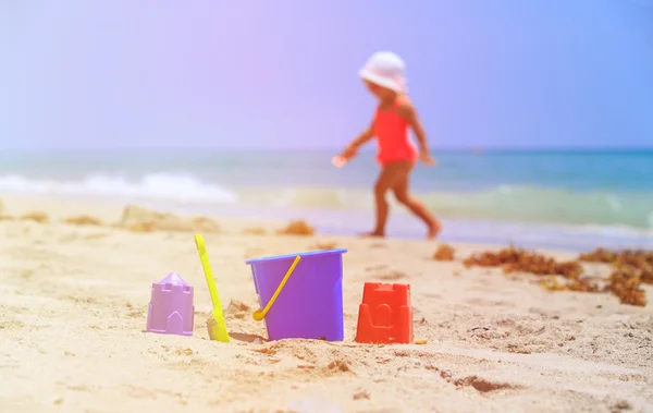 Dětské hračky a holčička hraje na pláži — Stock fotografie