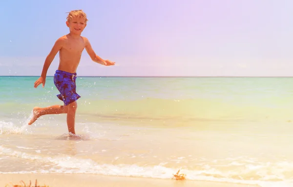 Mały chłopiec biegną rozpryskujących na plaży — Zdjęcie stockowe