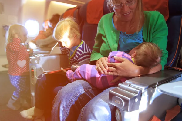 Madre con bebé recién nacido, hijo pequeño e hija viajan en avión — Foto de Stock