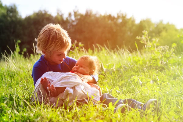 Pojke anläggning nyfödda lillasyster i sommar natur — Stockfoto