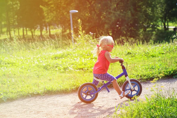 Милая маленькая девочка на беговом велосипеде летом — стоковое фото