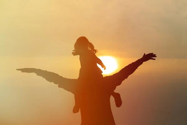 Father and little daughter on shoulders play at sunset sky — Stock Photo, Image