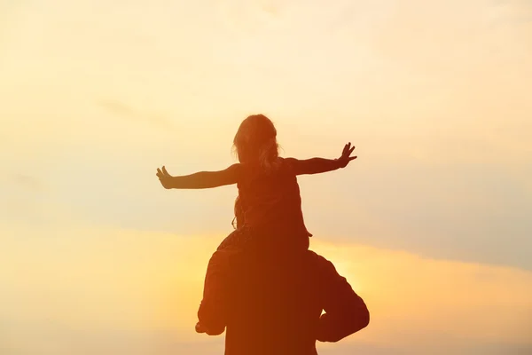 Father and little daughter on shoulders play at sunset sky — Stock Photo, Image
