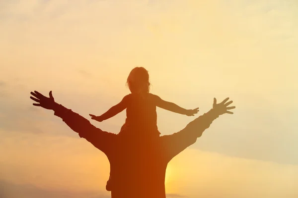 父亲和肩膀上的小女儿玩在落日的天空 — 图库照片