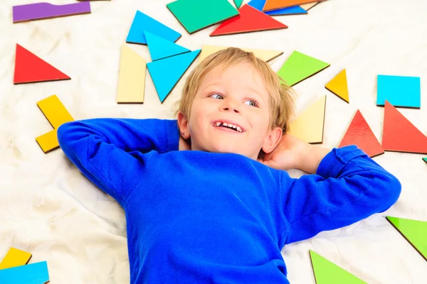 Boy lying with puzzle toys — Stock Photo, Image