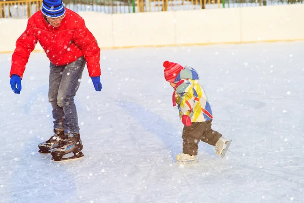Отец учил дочь кататься на коньках зимой — стоковое фото