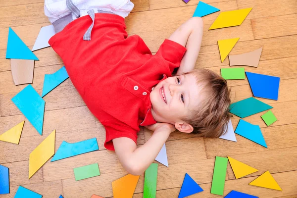 Boy lying with puzzle toys — Stock Photo, Image