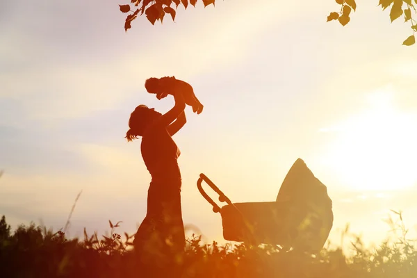 Silhuetter av mamma med barn och barnvagn — Stockfoto