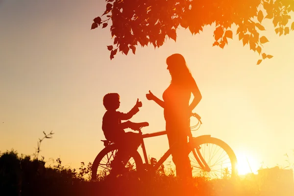 Силует щасливої матері і сина на велосипеді на заході сонця — стокове фото