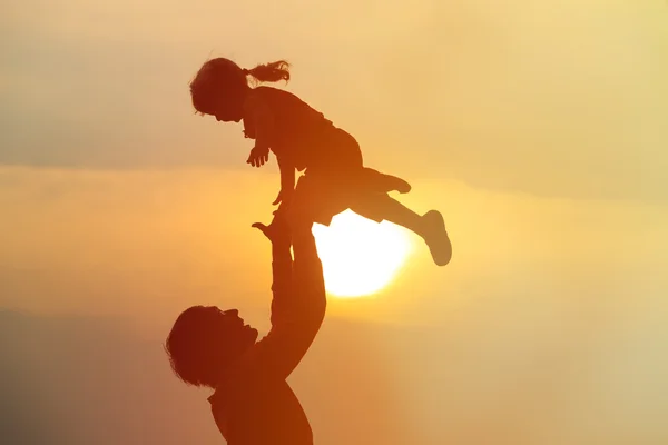 Père et petite fille silhouettes jouent au coucher du soleil — Photo