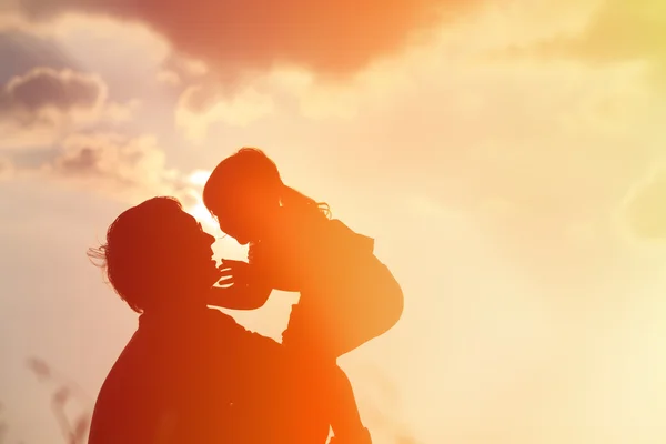 Padre e piccola figlia silhouette giocano al tramonto — Foto Stock